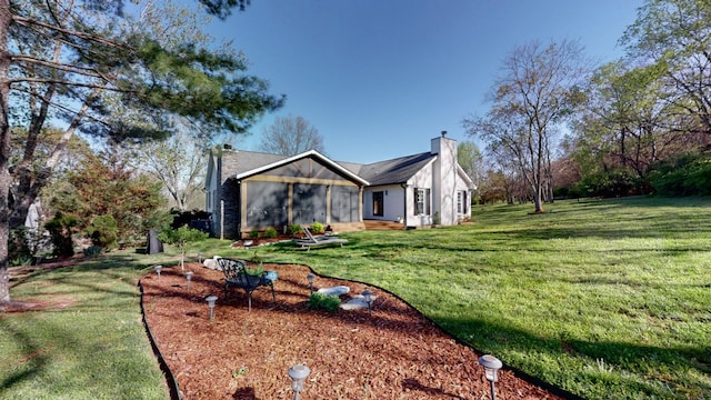 exterior space featuring a yard, a sunroom, and a chimney