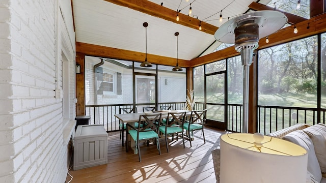 sunroom featuring beamed ceiling and outdoor dining space