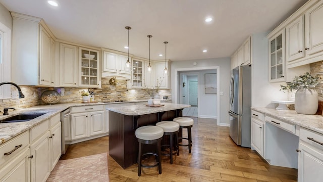 kitchen featuring tasteful backsplash, appliances with stainless steel finishes, a sink, and a kitchen breakfast bar
