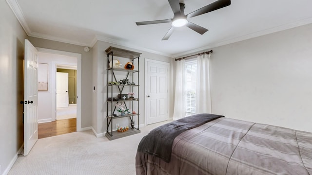 bedroom featuring ornamental molding, baseboards, a ceiling fan, and light colored carpet