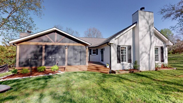 rear view of house with brick siding, a yard, a sunroom, and a chimney