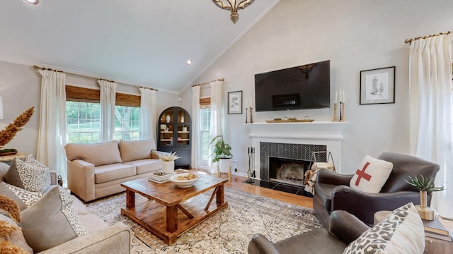 living room featuring high vaulted ceiling, recessed lighting, a tile fireplace, and wood finished floors
