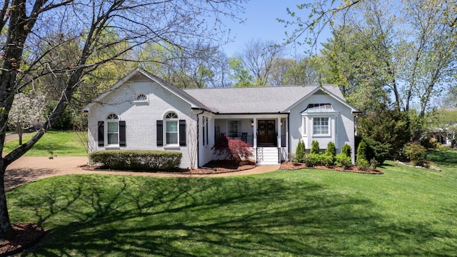 view of front of house with a shingled roof, brick siding, and a front lawn