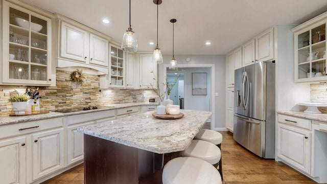 kitchen with stainless steel fridge with ice dispenser, a center island, decorative backsplash, and black electric stovetop