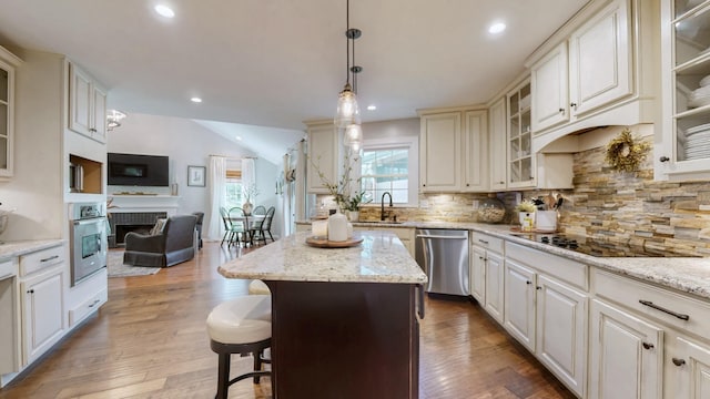 kitchen with tasteful backsplash, a sink, wood finished floors, stainless steel appliances, and lofted ceiling
