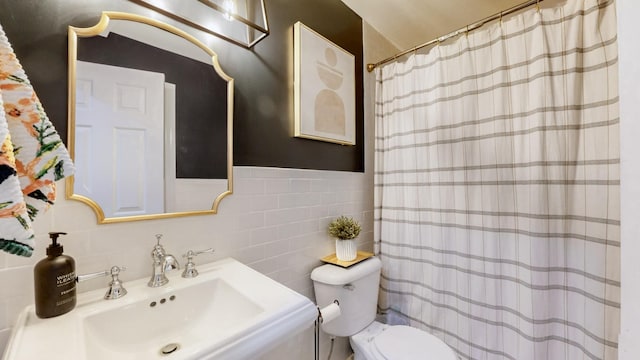 bathroom featuring toilet, a shower with shower curtain, a sink, and tile walls