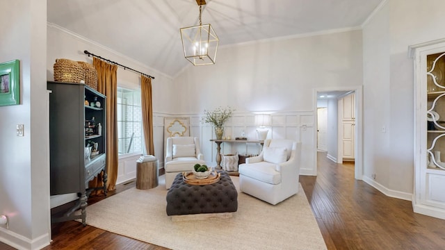 living area with crown molding, wood finished floors, a notable chandelier, and baseboards