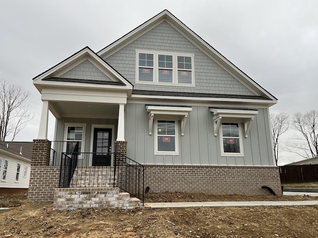 view of front facade with covered porch, brick siding, and board and batten siding