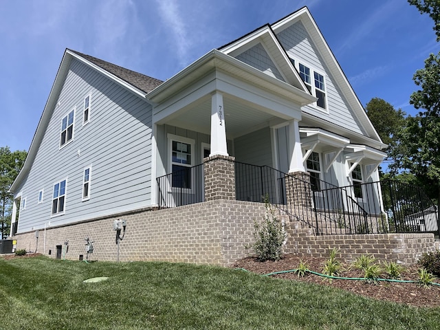 view of front of home featuring covered porch, a front lawn, and central air condition unit