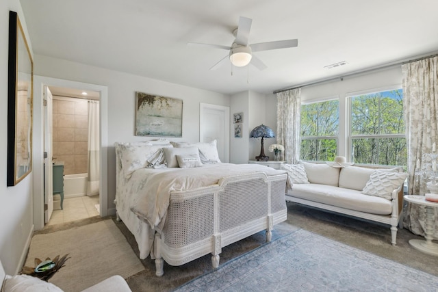bedroom featuring ensuite bath, visible vents, and ceiling fan