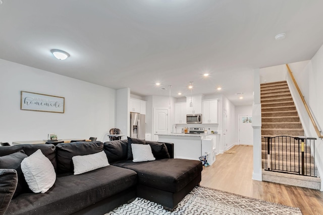 living room with recessed lighting, stairs, light wood finished floors, and baseboards