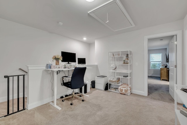 carpeted office with baseboards and attic access