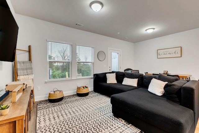 living room with wood finished floors, baseboards, and visible vents