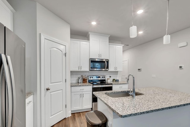 kitchen featuring a kitchen island with sink, visible vents, stainless steel appliances, a sink, and wood finished floors