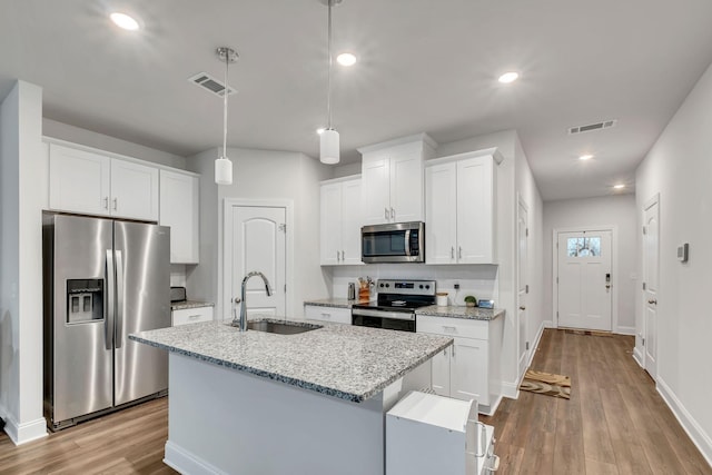 kitchen featuring light wood finished floors, a sink, visible vents, and stainless steel appliances
