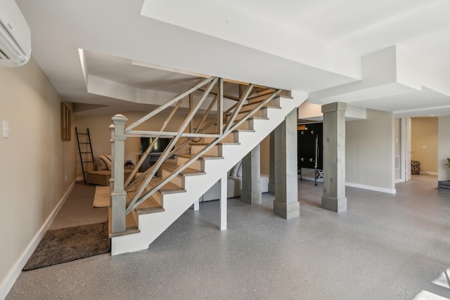 finished basement featuring a wall mounted AC, stairway, and baseboards