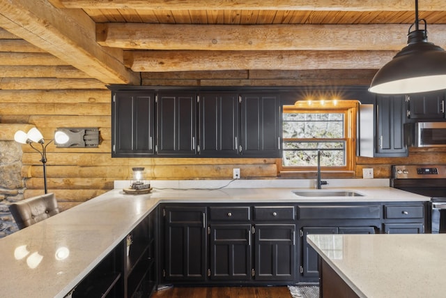 kitchen featuring log walls, beamed ceiling, dark cabinetry, appliances with stainless steel finishes, and a sink