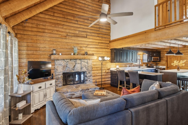 living area with dark wood finished floors, a ceiling fan, a stone fireplace, a high ceiling, and log walls