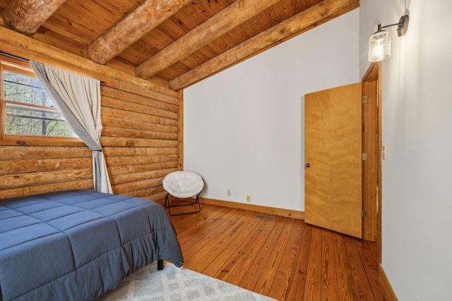 bedroom with beamed ceiling, log walls, hardwood / wood-style flooring, and wood ceiling