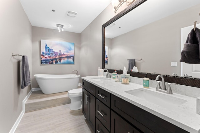 bathroom featuring wood finished floors, double vanity, a sink, and a freestanding tub