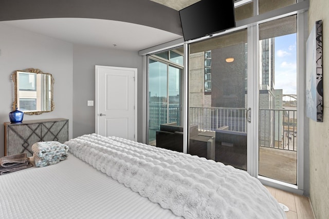 bedroom with access to exterior and wood finished floors