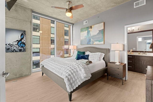 bedroom with a sink, visible vents, a wall of windows, and light wood finished floors