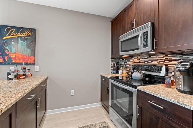 kitchen featuring tasteful backsplash, light stone countertops, dark brown cabinetry, and stainless steel appliances
