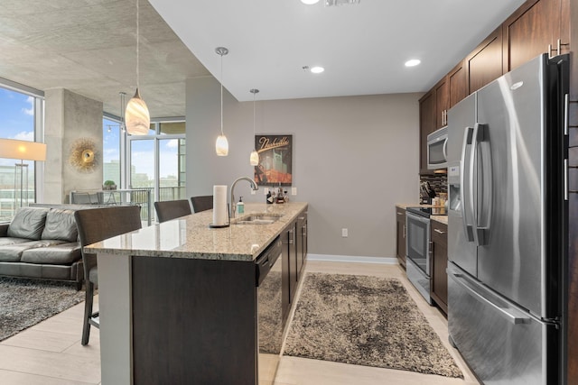 kitchen with stainless steel appliances, light wood-style flooring, a breakfast bar, and a sink