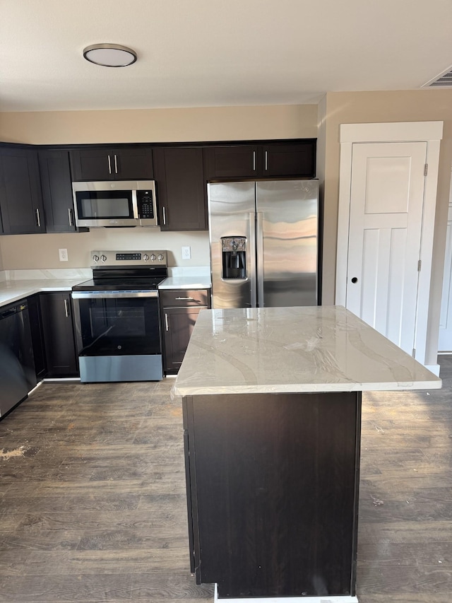 170 Cardinal Crk, Clarksville, TN 37040 - kitchen with stainless steel appliances, light stone countertops, wood finished floors, a kitchen island, and dark cabinetry