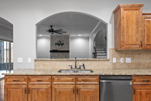 kitchen featuring ceiling fan, stainless steel dishwasher, a sink, light stone counters, and ornamental molding