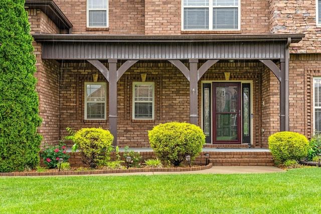 property entrance with a lawn, covered porch, and brick siding