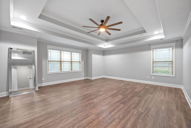 unfurnished living room with visible vents, ornamental molding, dark wood-type flooring, a raised ceiling, and a ceiling fan