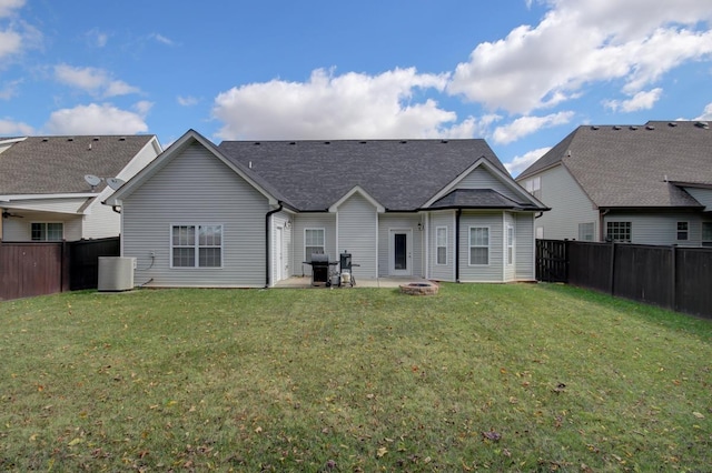 back of house featuring cooling unit, a yard, a fenced backyard, and a fire pit