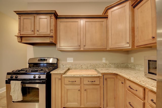 kitchen with light stone counters, light brown cabinetry, and stainless steel appliances