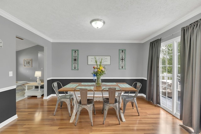 dining area with ornamental molding, baseboards, wood finished floors, and a textured ceiling