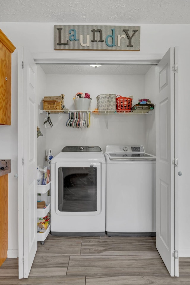 washroom featuring washing machine and clothes dryer, wood finished floors, and laundry area