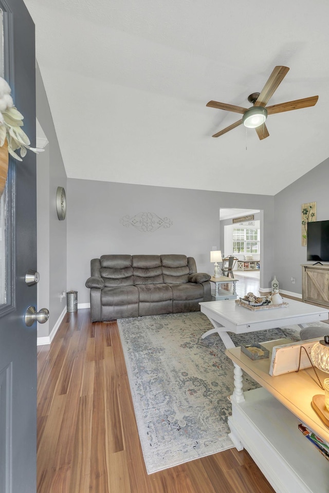 living area featuring baseboards, a ceiling fan, wood finished floors, and lofted ceiling