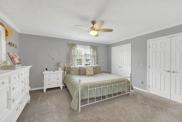 carpeted bedroom featuring a textured ceiling, two closets, and crown molding