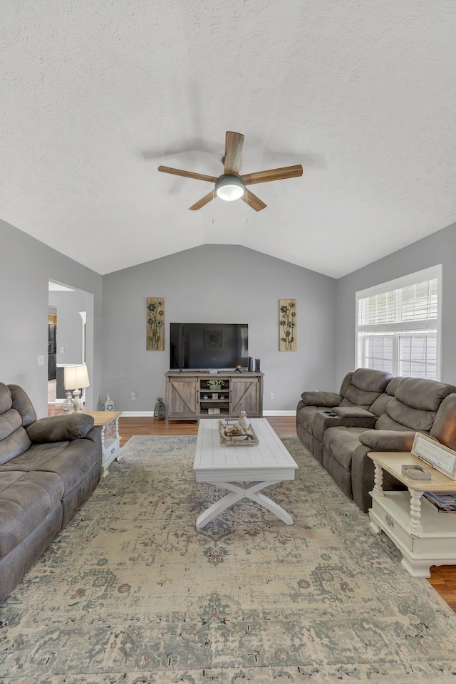 living area featuring baseboards, vaulted ceiling, a ceiling fan, and wood finished floors