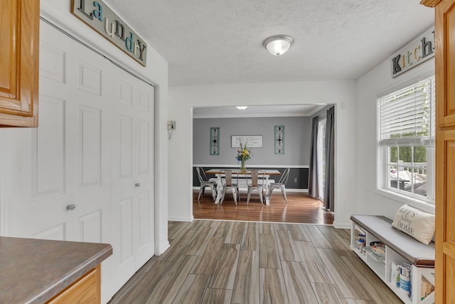 hallway featuring baseboards, wood finished floors, and a textured ceiling