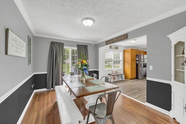 dining room with baseboards, light wood-style flooring, a textured ceiling, and crown molding