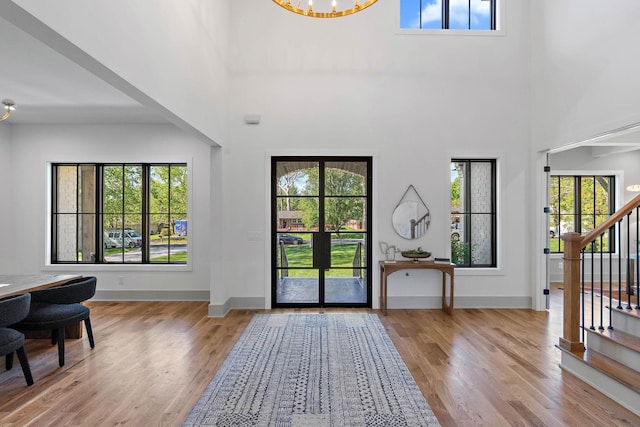 entryway with a towering ceiling, baseboards, wood finished floors, and stairs