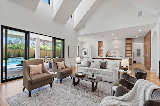 living room with light wood finished floors, baseboards, and high vaulted ceiling