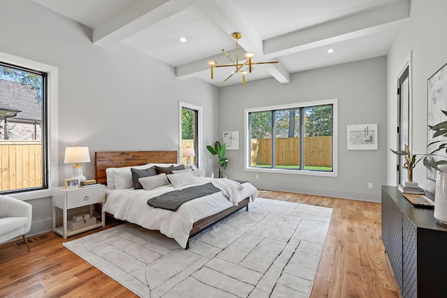 bedroom featuring light wood-style floors, a notable chandelier, beam ceiling, and multiple windows