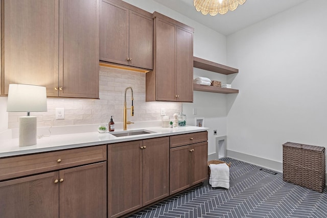 kitchen featuring a sink, tasteful backsplash, baseboards, open shelves, and light countertops