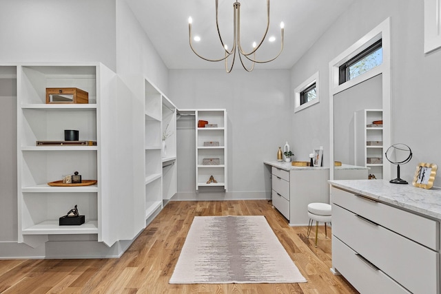 walk in closet featuring an inviting chandelier and light wood-style floors