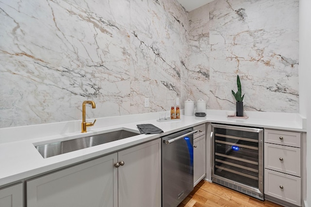 bar featuring wine cooler, a sink, and light wood-style floors