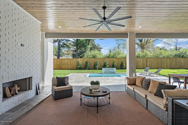 view of patio / terrace featuring a fenced backyard, an outdoor living space with a fireplace, and a ceiling fan