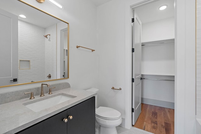 full bathroom with a walk in closet, toilet, walk in shower, and vanity