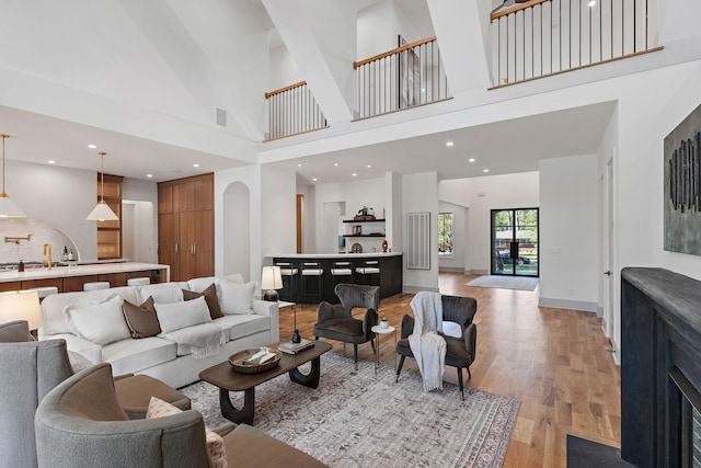living area featuring light wood-style floors, a towering ceiling, and baseboards